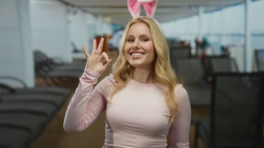 Tavşan kulaklı genç bir sarışın gemi güvertesinde gülümserken hoş bir jest yapar. Rahatlatıcı bir ortamın ortasında neşeli ve neşeli bir hava yayar..