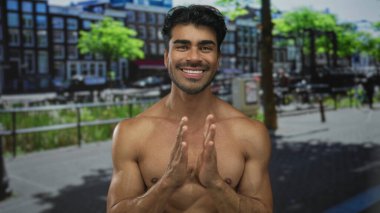 Genç İspanyol tişörtsüz adam canlı güneşli bir caddede el çırpıyor. Minnettarlık..