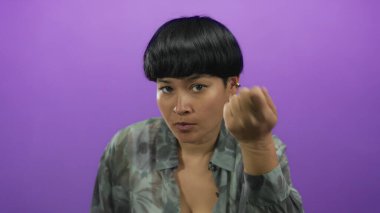 İzole edilmiş mor arkaplan önünde el kol hareketi yapan bir kadın iletişim veya etkileşim kuruyor.