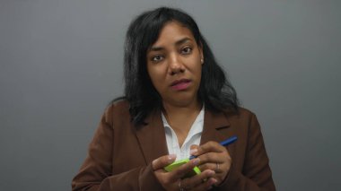 Stüdyoda elinde kalemle ve özenli bir ifadeyle yumuşak ışıklandırma altında yapışkan bir not yazan kadın, odaklanma planlaması.