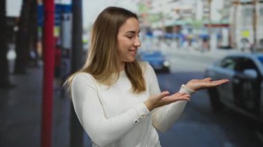 Canlı bir şehir caddesinde, uzanmış elleriyle gülümseyen bir kadın, şehir hayatını ve modern moda tarzını gözler önüne seren sıradan bir açık hava ortamında merak ve heyecan ifade ediyor..