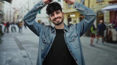 Şehirdeki sokak ortamında gülümseyen genç adam, şehir arka planında bulanık kot ceket giyiyor..