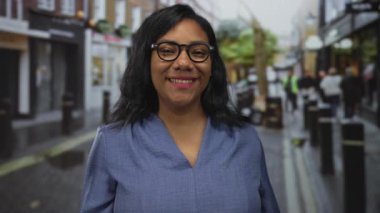 Mavi bluz giyen ve gözlüklü bir kadın gün ışığında dudaklarıyla öpücük yolluyor..