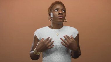 Genç Afrikalı Amerikalı kadın, stüdyoda şeftali duvarlı altın kalp kolyesini ayarlıyor..