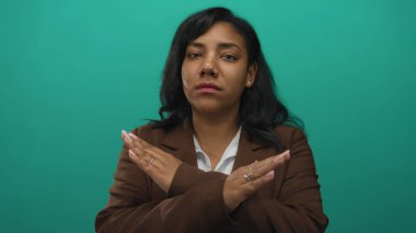 Kahverengi ceketli Afrikalı Amerikalı kadın stüdyoda ciddi ifadeleri olan avuç içlerini çapraz gösteriyor..