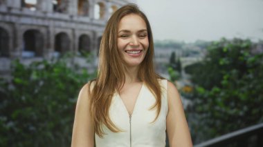 Genç beyaz kadın Roma 'daki antik kolezyum binasından önce gülümsüyor; keyifli yolculuk anı.