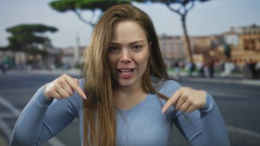 Genç kadın kulaklarını kapatıyor sonra da bulanık araba farları ve kentsel binalar arasında kalabalık caddede el sallıyor; heyecan.