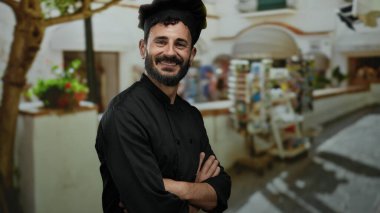 Siyah üniformalı, kendine güvenen İspanyol aşçı. Canlı bir sokakta gülümsüyor. Piyasa geçmişi ve yerel mimarisi bulanık.