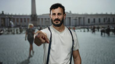 Eski Roma 'da pantolon askısı takan İspanyol bir adam bulanık dikilitaşlı arka planda şehir keşfi havasını yakalıyor..