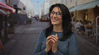 Orta yaşlı bir kadın, gündüz vakti kaldırım kafesi terasının dışındaki işlek bir caddede el sıkıştı; memnuniyet.