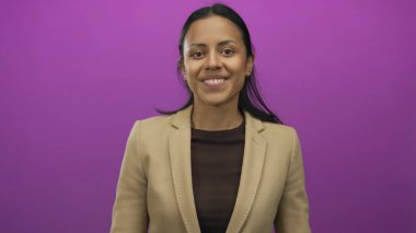 İzole edilmiş pembe bir arkaplan karşısında kendine güvenen genç bir kadın, pozitiflik ve zarafet saçıyor..