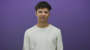 Gözlüklü bir adam stüdyoda gülümsüyor ve elinde mor duvarlı bir pasaport tutuyor; küresel kimlik hareketliliği umudu.