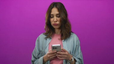 Akıllı telefonu canlı pembe arka plana karşı kullanan kadın renkli bir ortamda modern teknoloji etkileşimi sergiliyor..