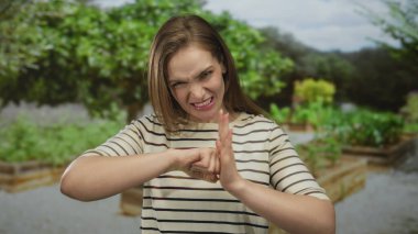 Yeşil park yolunda kaşlarını çatarken yumruğunu sıkan ve boş bir yeri işaret eden kadın; öfke..