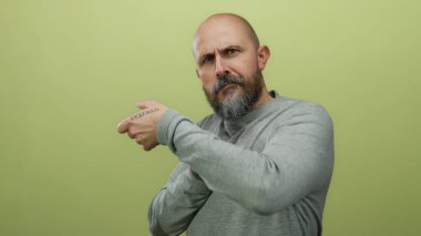 Bald man with beard miming rope pulling against yellow background in a candid portrait.