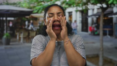 Afrika kökenli Amerikalı kadınlar ellerini ağızlarına dayayıp ağaçların altında ve şemsiyelerin altında bağırıyorlar..