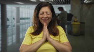 İspanyol kadın yoğun bir havaalanı terminalinde el ele tutuşup dua ediyor. Minnettarlık..