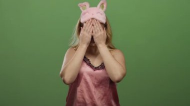 Pembe gece elbiseli bir kadın yeşil arka planda poz veriyor, neşe saçıyor ve enerjik titreşimler yayıyor, canlı ve eğlenceli bir atmosfer yaratıyor..