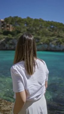 Santanyi, Mallorca 'da, açık mavi bir gökyüzünün altındaki Akdeniz sahilinin manzarasının tadını çıkaran bir kadın..