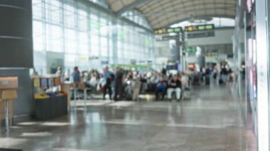 Yoğun havaalanı terminalindeki bulanık gezginler, 1. Terminalde odakları kesilmiş insanlar banklarda oturuyor, ferah iç mekan ve modern mimari sergiliyorlar.