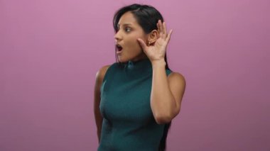 Soyutlanmış pembe arka planı olan genç bir kadın yeşil kolsuz bir bluz giyiyor..