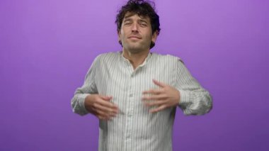 Mor bir arkaplan önünde poz veren kendinden emin bir adam çizgili bir gömlek giyiyor rahat bir ifade ve kapalı gözler takınıyor sakin ve sakin bir tavır sergiliyor..