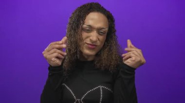 Transseksüel İspanyol kadın mor bir stüdyoda parmaklarıyla para hareketi yapıyor; açgözlülük zenginlik arzusu.