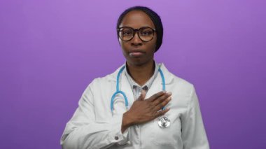 Beyaz önlüklü kadın doktor, göğüs göğüse tutuşmuş, mor arka planda yeminini simgeliyor..