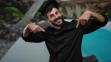 Otelde sakallı İspanyol bir aşçı, bir otelde sırıtıyor, ceketini doğal ve mavi suların arka planına gösteriyordu..