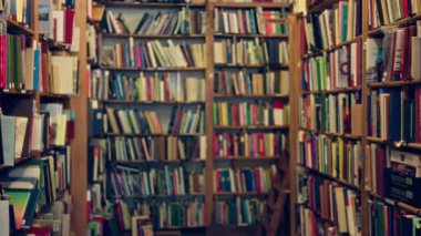 Raflarda sayısız kitapla bulanık kütüphane ayarları, öğrenim veya eğitim temaları için mükemmel bir kapalı hava yaratıyor.