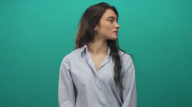 Çizgili gömlek ve küpe giyen kadın, stüdyoda başını döndürür; dinginlik tefekküre odaklanma.