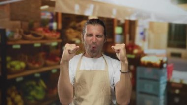 Sarışın, uzun saçlı bir adam marketin kalabalık koridorunda meyve vitrininin yanında yumruklarını sıkar..