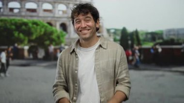 Roma, İtalya 'daki ikonik kolezyumun önünde kameraya gülümseyen İspanyol adam bir seyahat ve bağlantı anını yakalıyor..