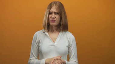 Profesyonel bir fotoğraf stüdyosunda genç sarışın kadın iki eliyle kulaklarını kapatır..