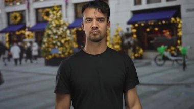 İspanyol asıllı genç bir adam, bayram süslemeleri ve yanan ağaçlarla çevrili, kendine güvenen ve saygılı bir tavrı somutlaştıran, şenlikli bir şehir caddesinde askeri selam veriyor..