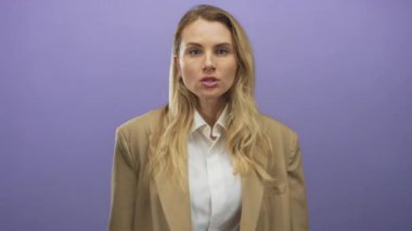 Sarışın bir kadın, mor bir arka plana karşı yumruğunu sıkarak öfkesini ifade ediyor. Güçlü bir duygu ve yoğunluk gösteriyor..