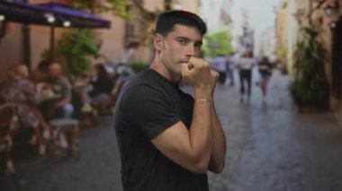 Siyah gömlekli, yumruklarını sıkmış bir adam kaldırılmış bir kaldırım taşı sokakta; kararlılık dayanıklılığı.