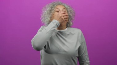 İzole edilmiş pembe arka planda hapşıran gri saçlı kadın, hareket ve duygu duygularını aktarıyor, yakın odaklı ve canlı renk kontrastı ile dinamik bir anda yakalandı.