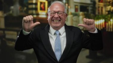 Takım elbiseli kıdemli bir adam kendini işaret ediyor. Arka planda bulanık mumlar ve mimariyle kilisenin içinde güvenle gülümsüyor. Neşe ve iş başarısını yansıtıyor..