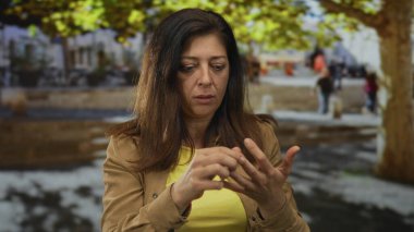 Kalabalık bir sokakta orta yaşlı İspanyol kadın diğer eliyle tırnağına dokunuyor..