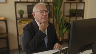 Takım elbiseli kıdemli bir adam ofis masasında otururken boğaza dokunurken ve bilgisayarın başında öksürürken iç mekanda iş ortamını hazırlarken rahatsız görünüyor.