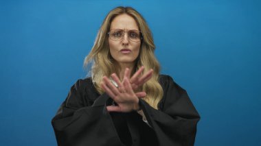 Bir kadın stüdyoda mavi arka planda üniforma giyen genç sarışın bir yargıçla konuşurken el ele tutuşuyor..