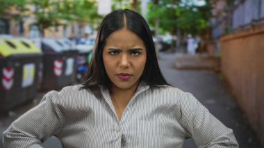 Şehir caddesinde çapraz silahlarla onaylamadığını belirten kadın, şehir manzarasının ortasında dikkat çekmek için bağırarak kararlı duruşunu vurguluyor..