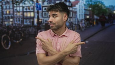 Pembe gömlekli adam şehir caddesinde bisikletlerin arasında kenara bakarken işaret ediyor; belirsizlik kararı.