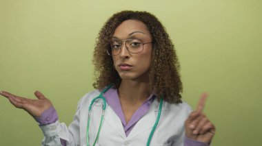 Doktor stetoskobu tutuyor ve açık yeşil bir stüdyo duvarına karşı avuç içi kaldırıyor; belirsizlik yansıması tefekkür.