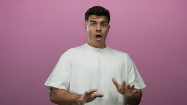 Genç adam canlı pembe bir arka plana karşı şaşkınlığını dile getiriyor. Elleri havada, günlük beyaz bir gömlek giyiyor. Duygusal ve anlamlı bir anın altını çiziyor..