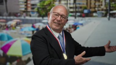 Takım elbiseli kıdemli bir adam sahilde renkli şemsiyelerin olduğu canlı bir sahneyi işaret ediyor..