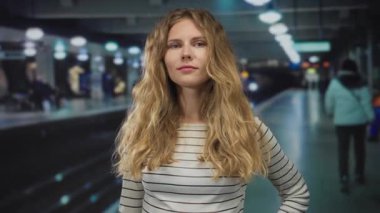 İstasyon çerçevesinde kendini gösteren parmaklı bir kadın, dalgalı saçlı ve kendine güvenen bir duruş sergileyen sarışın bir genç portreyi yakalıyor..