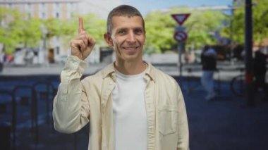 Canlı bir sokak ortamında, dışarıda el kol hareketi yapan beyaz bir adam parmağını açık gökyüzü ve canlı şehir atmosferiyle bulanık bir şehir arka planına doğrultuyor..
