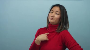 Kendine güveni olan bir kadın kırmızı süveter giyer ve soyutlanmış mavi arkaplan giyer. Bu gurur ve kendini tanıma anlamına gelir..